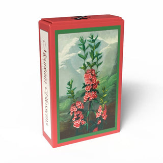 A red box labeled “Mountain Blossoms | 99 Piece Jigsaw Puzzle” by Penny Puzzle, featuring an illustration of pink flowers and green leaves in a mountain landscape inspired by the vintage botanical art of the Temple of Flora, shown against a white background.