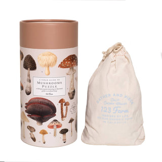 The Mushrooms | 500 Piece Jigsaw Puzzle by 123 Farm comes in a cylindrical container with woodland fungi illustrations and includes a drawstring cloth bag—perfect for mushroom enthusiasts.