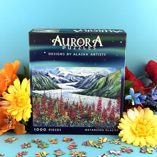Aurora Puzzles' Matanuska Glacier | 1,000 Piece Jigsaw Puzzle showcases glacier artwork with vibrant flowers and loose pieces on a blue background. This eco-friendly puzzle comes in a sturdy box, perfect for Alaskan scenery lovers.