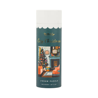 A cylindrical box labeled “Cozy Christmas | 500 Piece Jigsaw Puzzle” from My Mind’s Eye, featuring an illustration of a festive living room with a Christmas tree and fireplace. This cheerful holiday puzzle includes shimmering gold foil accents for extra sparkle and seasonal delight.