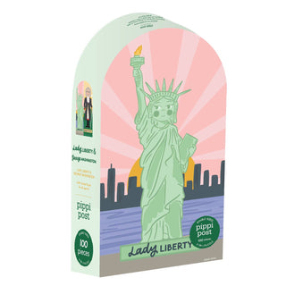 The George Washington Lady Liberty | Double Sided 100 Piece Jigsaw Puzzle by Pippi Post features an illustrated Statue of Liberty with sunglasses against a city skyline and pink sunburst background, with Lady Liberty and Pippi Post on the box.
