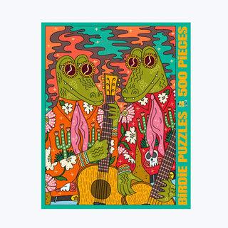 Two cartoon alligators in colorful shirts play guitars amid flowers and foliage on the cover of Birdie Puzzles’ vibrant “Sin City” 500-piece jigsaw puzzle, printed on sturdy Blue Kappa chipboard made from recycled materials.