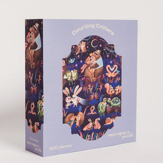 The Once Upon A Puzzle “Courting Critters” 500 piece jigsaw puzzle features illustrated animals dancing and interacting on a dark, whimsical woodland background.