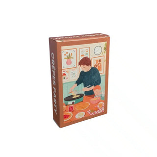 The Trevell “Crepes Party | 99 Piece Jigsaw Puzzle” comes in a box featuring an illustration of a person making crêpes in a cozy kitchen filled with ingredients and decorated walls, capturing the charm of this delightful puzzle.