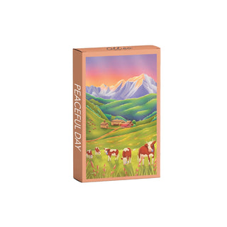 The Peaceful Day | 99 Piece Jigsaw Puzzle by Olleo Puzzles features an alpine evening scene with cows in a green valley, farmhouses, and snow-capped mountains beneath a colorful sky on its rectangular box.