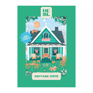 Illustration of a green cottage with porch, outdoor furniture, plants, and animals. Text: HEOL and COTTAGE D’ÉTÉ with a blue label "UNE PETITE PAUSE !". Cottage D’été | 99 Piece Jigsaw Puzzle by Heol Editions, made in France.