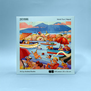 The StoPuzzle Napoli 500 Piece Jigsaw Puzzle features Andrea Boatta's illustrated seaside scene of Naples with people enjoying the coast. The box reads "World Tour | Napoli" and highlights that it’s made in Italy.