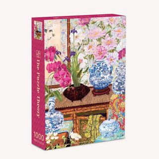 A 1,000-piece jigsaw puzzle box from The Puzzle Theory featuring the “Blue and White Dragons” design—an illustration of blue and white vases, pink orchids, and elegant floral arrangements on a wooden table inspired by the charming style of John Powell art.