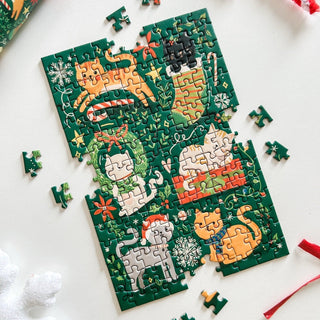 A partially completed Spaghetti Tree “Meowy Christmas” 150-piece jigsaw puzzle, featuring illustrations of five cats in various poses surrounded by snowflakes and Christmas-themed decorations on a green background.