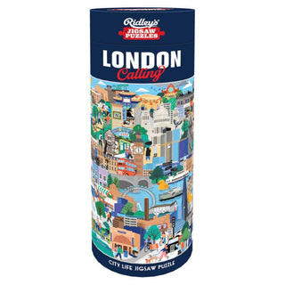 A cylindrical box labeled “London Calling” and featuring colorful illustrations of London city scenes holds the Chronicle Books London Calling City Life 1,000 Piece Jigsaw Puzzle, which captures the vibrant charm of city life.