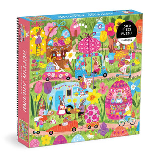 The Hoppin' Around 500 piece jigsaw puzzle by Mudpuppy features a lively outdoor scene of rabbits driving cars and riding bikes—a colorful, flower-filled family puzzle illustrated by Jenny Miriam, perfect for all ages.