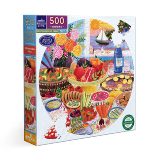 The Mediterranean Table | 500 Piece Jigsaw Puzzle by eeBoo comes in a round box and showcases a vibrant table with food, fruits, flowers, water bottle, and sailboat, all crafted from sustainably sourced materials.