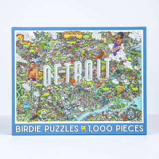 The Detroit | 1,000 Piece Jigsaw Puzzle by Birdie Puzzles features a colorful illustrated map of Detroit with local landmarks and cartoon characters—a fun gift for Detroit lovers.