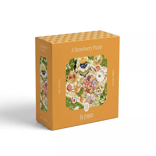 Bright orange box labeled “A Strawberry Picnic” featuring an illustration of a strawberry-filled picnic scene; this delightful 280-piece jigsaw puzzle by la pauz is perfect for a cozy afternoon.