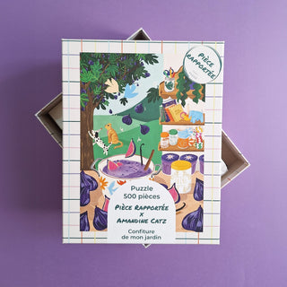The Confiture De Mon Jardin 500 Piece Jigsaw Puzzle by Pièce Rapportée features a charming illustrated garden with cats, fig jam jars, and a tree on a purple background.