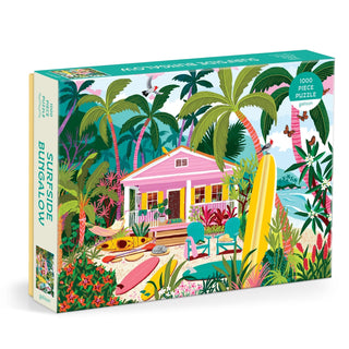 The Surfside Bungalow | 1,000 Piece Jigsaw Puzzle by Galison features a vibrant illustration of a pink tropical bungalow with palm trees, surfboards, and beach scenery.