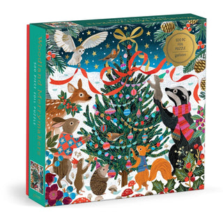 The Galison Victoria Ball Woodland Merrymakers 500 Piece Jigsaw Puzzle comes in a box featuring woodland animals decorating a Christmas tree with ornaments, ribbons, and garlands in a festive winter forest scene. Beautiful foil accents add shimmer and sparkle to this holiday jigsaw.