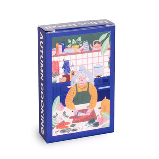 A blue box labeled Trevell Autumn Cooking | 99 Piece Jigsaw Puzzle features Marie Boiseau’s illustration of an older woman chopping vegetables in a vibrant kitchen, inviting you to enjoy this cozy autumn-themed puzzle.