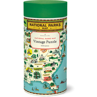 Cylindrical box with green lid labeled Cavallini & Co. National Parks Map | 1,000 Piece Jigsaw Puzzle, featuring illustrated U.S. national parks on the packaging.