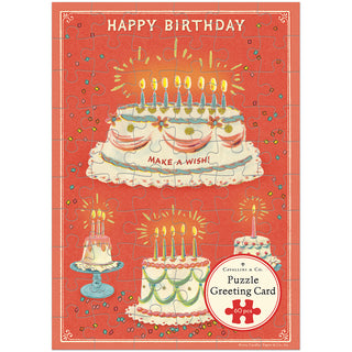 The Cavallini & Co. Happy Birthday Cake 60 Piece Greeting Card Jigsaw Puzzle features illustrated birthday cakes with candles and the text "HAPPY BIRTHDAY" and "MAKE A WISH!" on a red background.