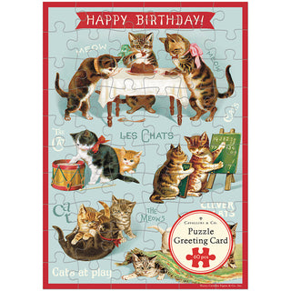 The Happy Birthday Cat's Play 60 Piece Greeting Card Jigsaw Puzzle by Cavallini & Co. features cats in clothing celebrating around a table with a Happy Birthday banner on a completed puzzle card.