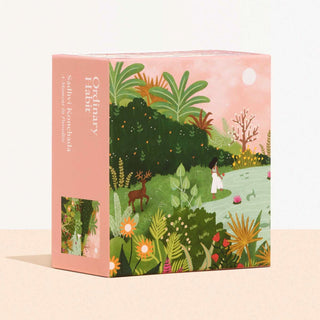 A Moment In Paradise by Sadhvi Konchada is a 100-piece jigsaw puzzle from Ordinary Habit, featuring a woman in a lush landscape with plants, flowers, pond, and deer under a pink sky—made from recycled materials.
